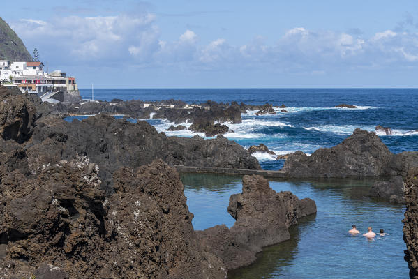 Three men bathing in the natural pools of Porto Moniz, Madeira region, Portugal.