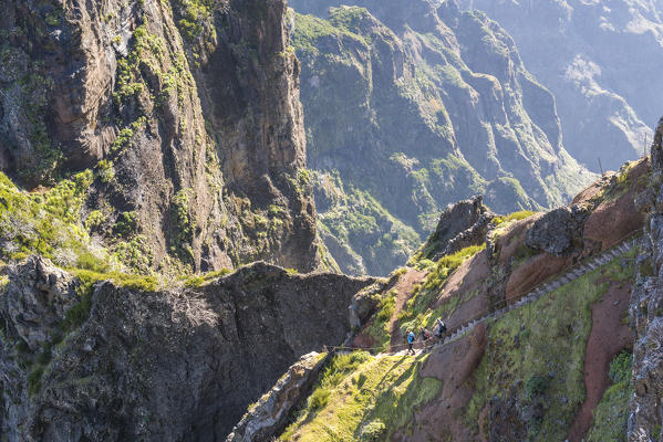 Three people descenging the steps on the trail from Pico Ruivo to Pico do Areeiro. Funchal, Madeira region, Portugal.