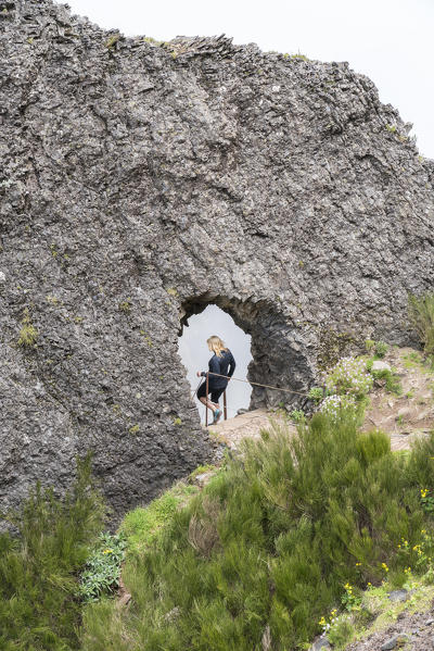 Woman passing through a rock tunnel on the trail at Pico do Areeiro. Funchal, Madeira region, Portugal.