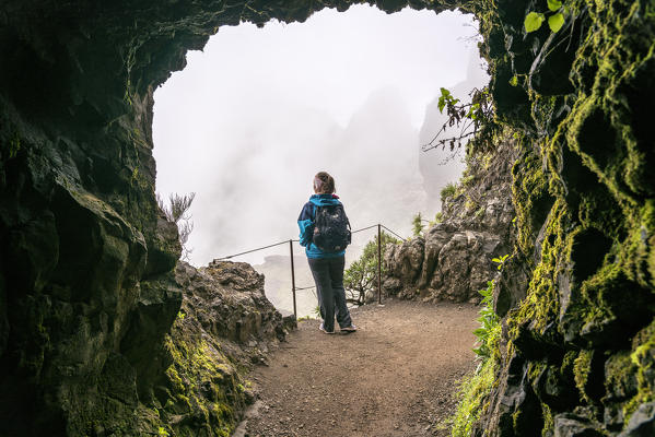 Woman admiring the Central Mountain Range covered in mist, on the trail from Pico Ruivo to Pico do Areeiro. Santana municipality, Madeira region, Portugal. (MR)