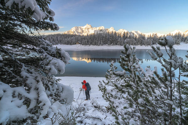 Photographer with tripod in the snow on the shore of Lake Palù, Malenco Valley, Sondrio province, Valtellina, Lombardy, Italy