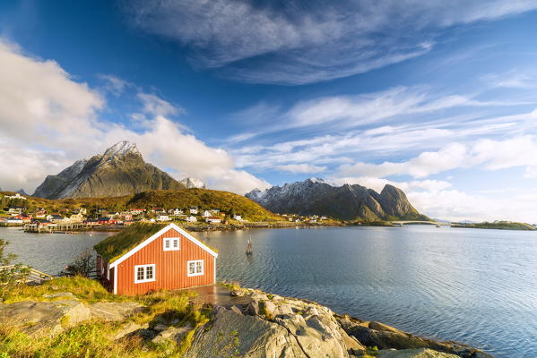 Iconic Rorbu with grass roof with Mount Olstind (Olstinden) on background, Reine, Moskenes, Nordland, Lofoten Islands, Norway