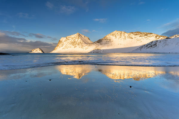 Snowy peaks mirrored in water, Haukland beach, Vestvagoy, Nordland, Lofoten Islands, Norway