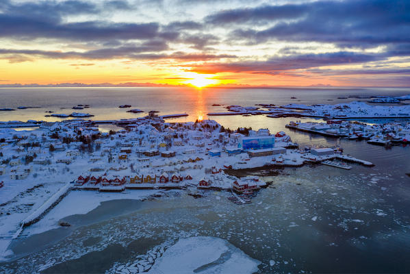 Aerial panoramic of the rising sun over Ballstad and icy sea, Vestvagoy, Lofoten Islands, Norway