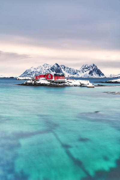 Rorbu on snowy islet in the turquoise sea, Svolvaer, Lofoten Islands, Norway