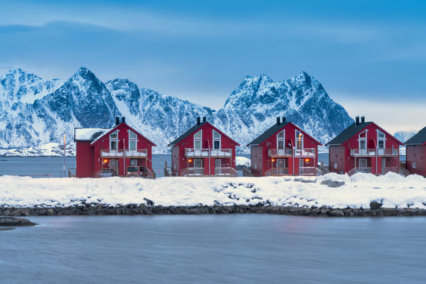 Dusk on red cabins (Rorbu) overlooking the icy sea, Svolvaer, Lofoten Islands, Norway