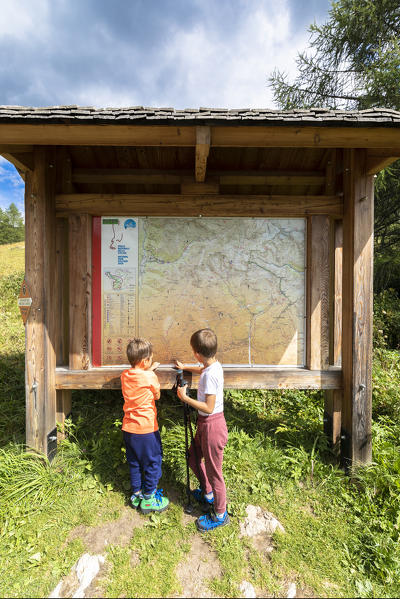 Children look at signboard of hiking trails, Val Canè, Temù, Valcamonica, province of Brescia, Lombardy, Italy