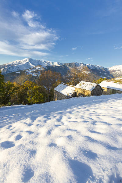 Snow covered huts surrounded by colorful trees in autumn, Bodone, Gravedona, Lake Como, Lombardy, Italy