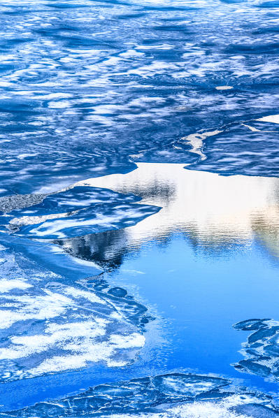 Ice melting on water surface of Lej da la Tscheppa during the thaw, St. Moritz, Engadin, canton of Graubunden, Switzerland