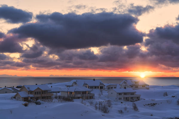 Dramatic sky at sunrise over traditional houses by the sea, Reine, Nordland, Lofoten Islands, Norway