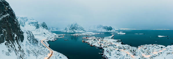 Aerial panoramic of coastal road and Reine village at dusk, Nordland, Lofoten Islands, Norway