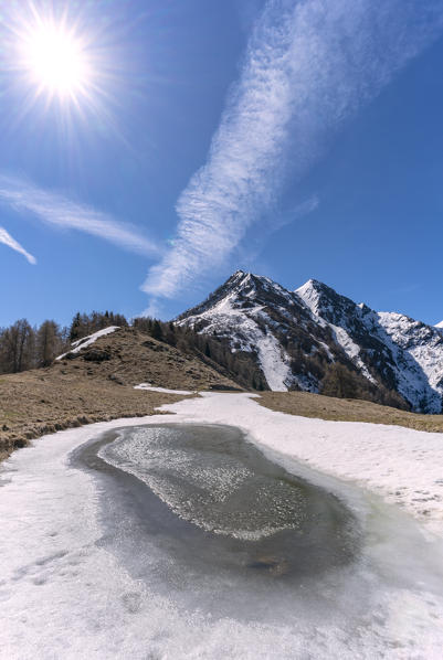 Ice during spring thaw at Alpe Piazza with Pizzo Dei Galli and Monte Olano in background, Val Gerola, Valtellina, Lombardy, Italy