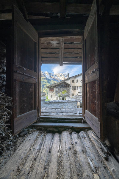 Traditional stone houses seen from inside of hut for wood storage, Soglio, Bregaglia Valley, canton of Graubunden, Switzerland