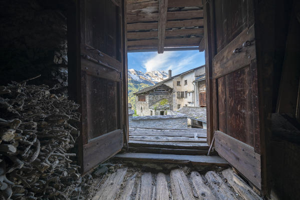 Traditional stone houses seen from inside of hut for wood storage, Soglio, Bregaglia Valley, canton of Graubunden, Switzerland