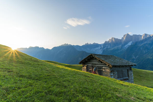 Sunburst over the green meadows of Tombal Alp, Soglio, Val Bregaglia, canton of Graubunden, Switzerland