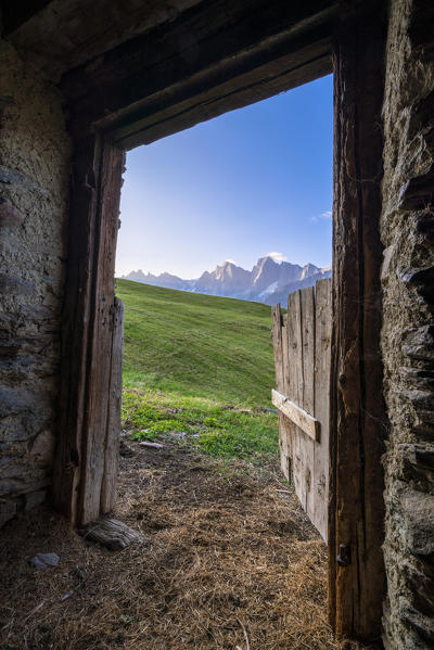 Piz Badile and Cengalo framed by the open door of a barn at Tombal Alp, Soglio, Val Bregaglia, canton of Graubunden, Switzerland