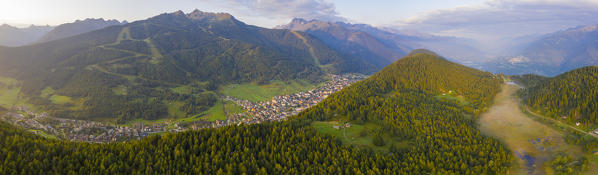 Aerial panoramic of woods in Pian di Gembro Nature Reserve with village of Aprica in background, Valtellina, Lombardy, Italy