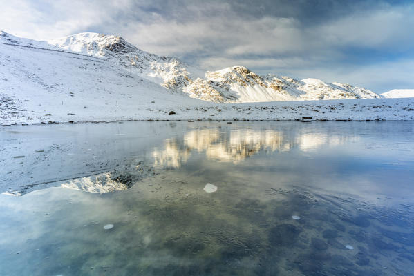 Filon del Mot covered with snow mirrored in the frozen lake, Braulio Valley, Stelvio Pass, Bormio, Valtellina, Lombardy, Italy