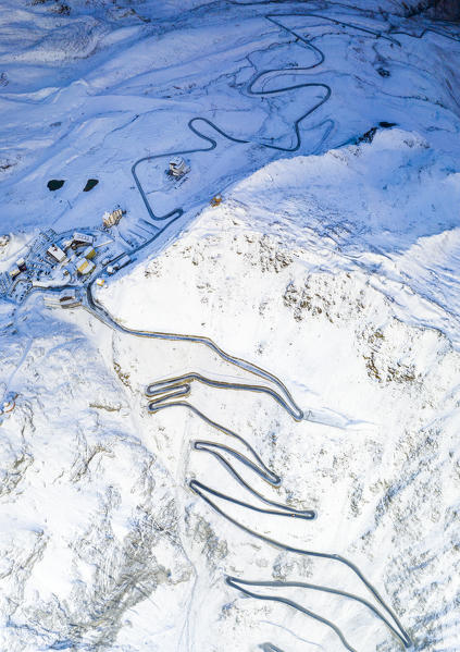 Aerial panoramic of Stelvio Pass and winding road covered with snow at dawn, Bolzano province, South Tyrol side, Italy