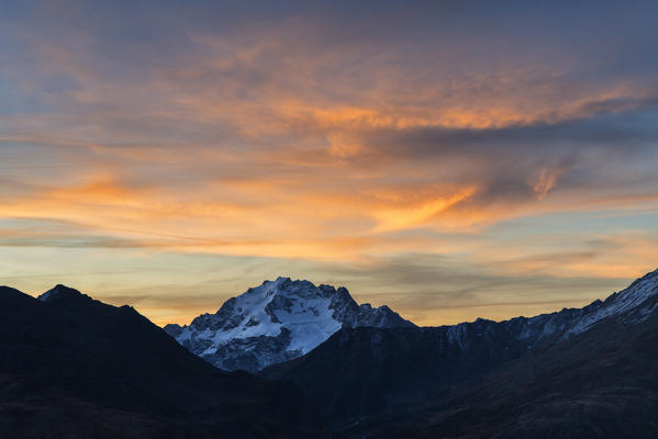 Dramatic sky at dawn over Cima Piazzi peak in autumn, Livigno, Valtellina, Sondrio province, Lombardy, Italy