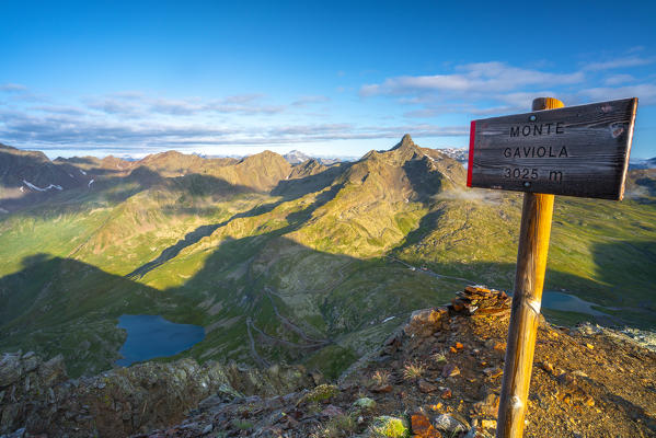 Signboard on top of Monte Gaviola with Gavia Pass mountain road and valley in background, Valtellina, Lombardy, Italy