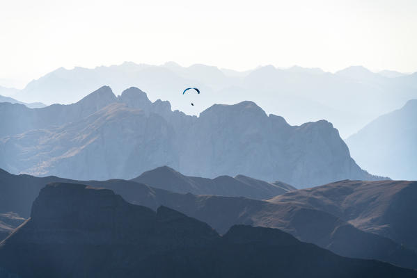 Paragliding at sunset over Val di Fassa in autumn seen from Sass Pordoi, Dolomites, Trentino, Italy