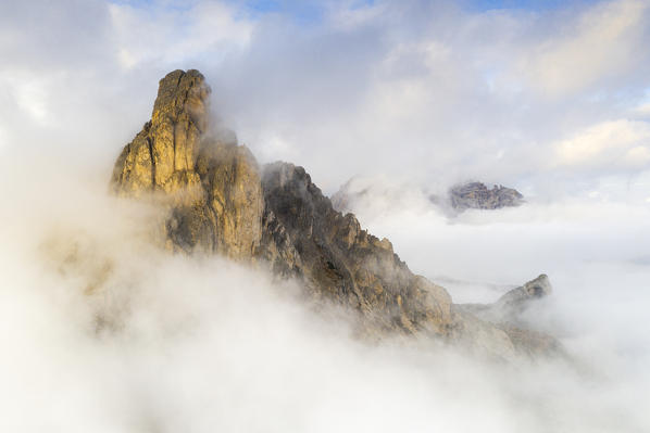 Sunset over Ra Gusela mountain emerging from autumn fog, aerial view, Giau Pass, Dolomites, Belluno province, Veneto, Italy