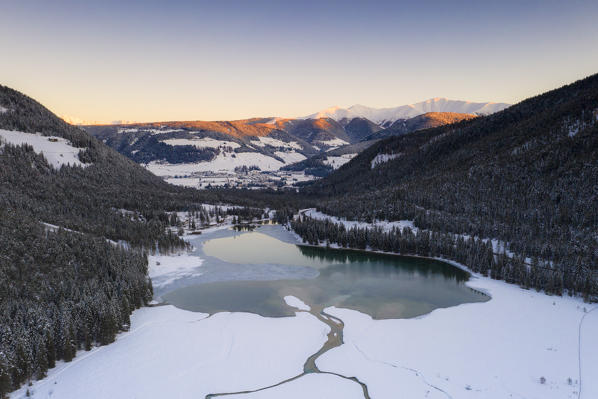 Lake Dobbiaco partially frozen surrounded by woods, Dobbiaco, Val Pusteria, Dolomites, Bolzano province, South Tyrol, Italy