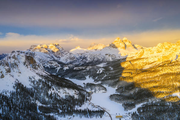 Sunset over Tre Cime di Lavaredo and Monte Piana covered with snow, aerial view, Misurina, Dolomites, Belluno, Veneto, Italy