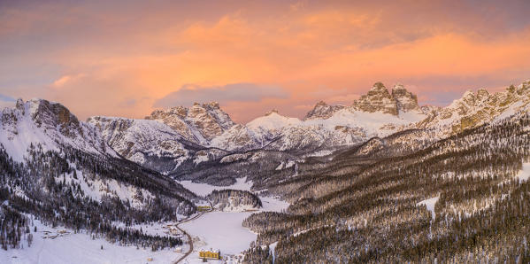 Sunset on Tre Cime di Lavaredo and woods covered with snow, aerial view, Misurina, Dolomites, Belluno province, Veneto, Italy