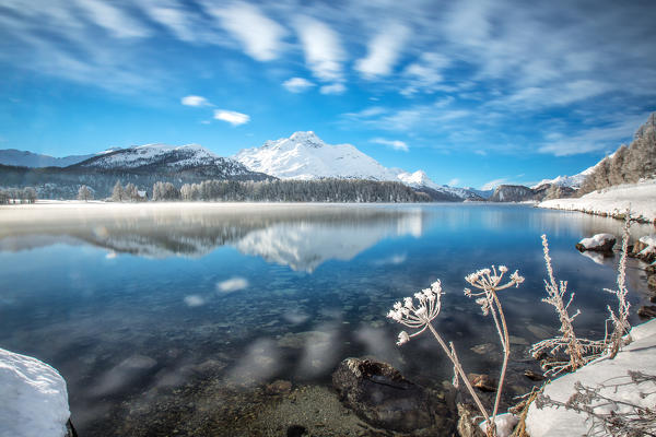 Winter clouds dancing in the wind reflecting in Lake Sils. Engadine. Switzerland