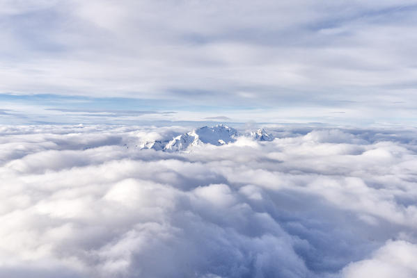 Aerial view of snowcapped Marmolada emerging from a sea of clouds, Dolomites, Trentino-Alto Adige, Italy