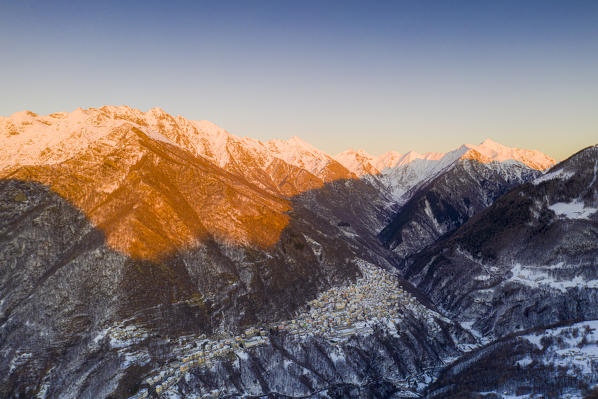 Sunset lit the snowy peaks above the village of Premana, Valsassina, Lecco province, Lombardy, Italy