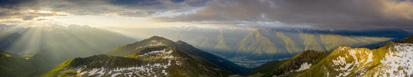 Panoramic of Orobie Alps and high Valtellina lit by sun rays at dawn, aerial view, Valmalenco, Sondrio province, Lombardy, Italy