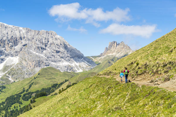 Mother and son walking on path towards Alpe di Tires hut and Denti di Terrarossa in summer, Dolomites, Trentino Alto Adige, Italy