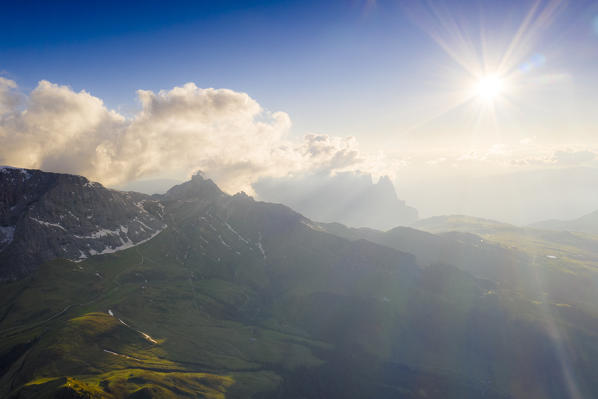 Backlit sunset over Denti di Terrarossa, Molignon and Sciliar mountains, aerial view, Seiser Alm, Dolomites, South Tyrol, Italy