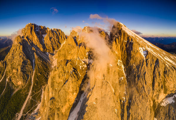 Aerial panoramic of Sassopiatto and Sassolungo majestic rock faces lit by sunset, Dolomites, Trentino-Alto Adige, Italy