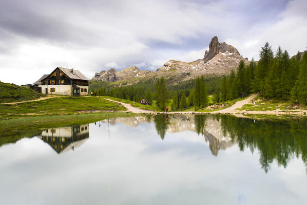 Hikers at Rifugio Croda da Lago with Becco di Mezzodì mirrored in Lake Federa, Ampezzo Dolomites, Belluno, Veneto, Italy