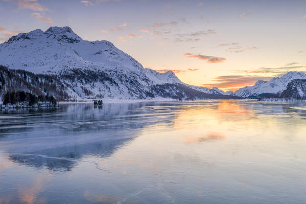 Burning sky at sunset on snowy Piz Da La Margna peak and frozen Lake Sils, canton of Graubunden, Engadine, Switzerland