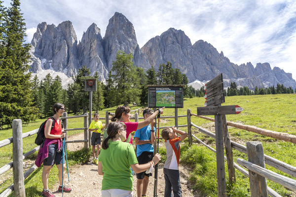 Mothers and children looking at the hiking signage along the Adolf Munkel trail, Val di Funes, South Tyrol, Dolomites, Italy