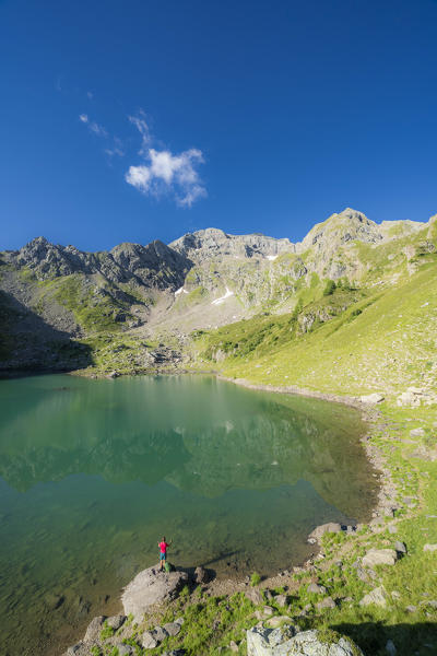 Hiker woman standing on rocks admiring Torena lakes, aerial view, Orobie Alps, Aprica, Val Belviso, Valtellina, Lombardy, Italy