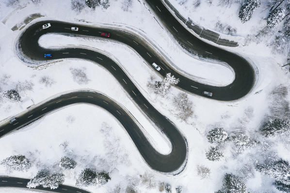 Aerial view of cars driving on narrow bends of mountain road in the snow