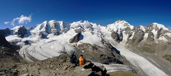Hikers looking at the vastness of the glaciers of Bernina from Diavolezza Refuge. Engadine, Canton of Graubunden, Switzerland Europe