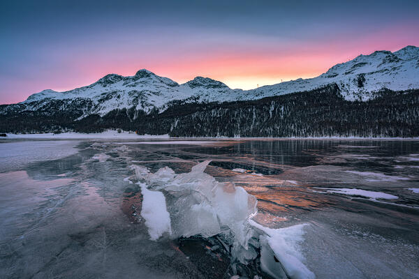 Ice blocks on frozen Lake Silvaplana framed by snowcapped mountains at dawn, Maloja, Engadine, Graubunden canton, Switzerland