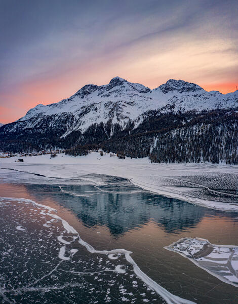 Winter sunrise on snowcapped mountains reflected in frozen Lake Silvaplana, Maloja, Engadine, Graubunden canton, Switzerland