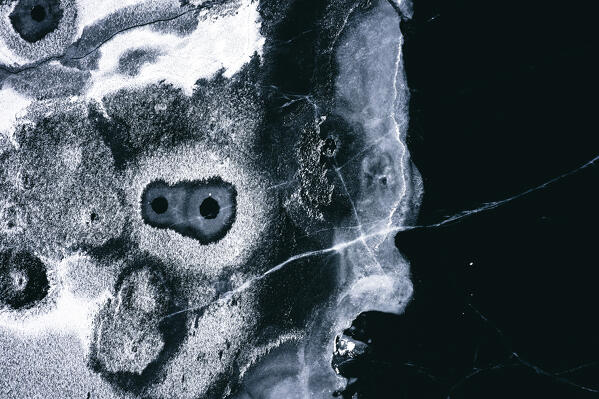 Aerial view of holes in the cracked ice covering the frozen Lake Silvaplana, Engadine, Graubunden canton, Switzerland