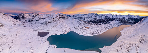 Winter sunrise over snowcapped mountains surrounding the frozen lake Bianco at Bernina pass, Graubunden, Engadin, Switzerland