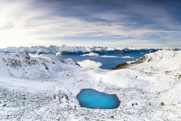 Aerial view of the Orobie Alps mountain range covered with snow and frozen Rogneda lake, Rhaetian Alps, Lombardy, Italy