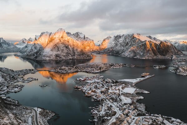 Winter sunrise over Mount Olstind and Reine Bay covered with snow, aerial view, Reine, Nordland, Lofoten Islands, Norway