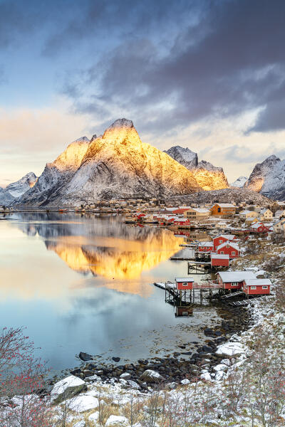 Snowcapped mountains reflected in the cold sea at sunrise, Reine Bay, Nordland county, Lofoten Islands, Norway